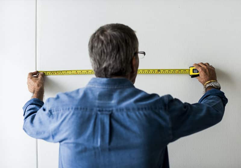 homem medindo a parede com trena