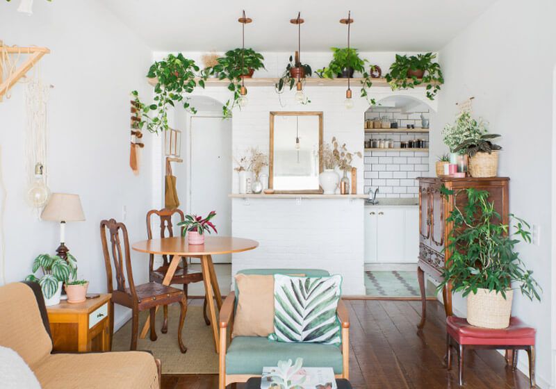 Sala pequena de apartamento decorada com móveis de madeira e plantas.