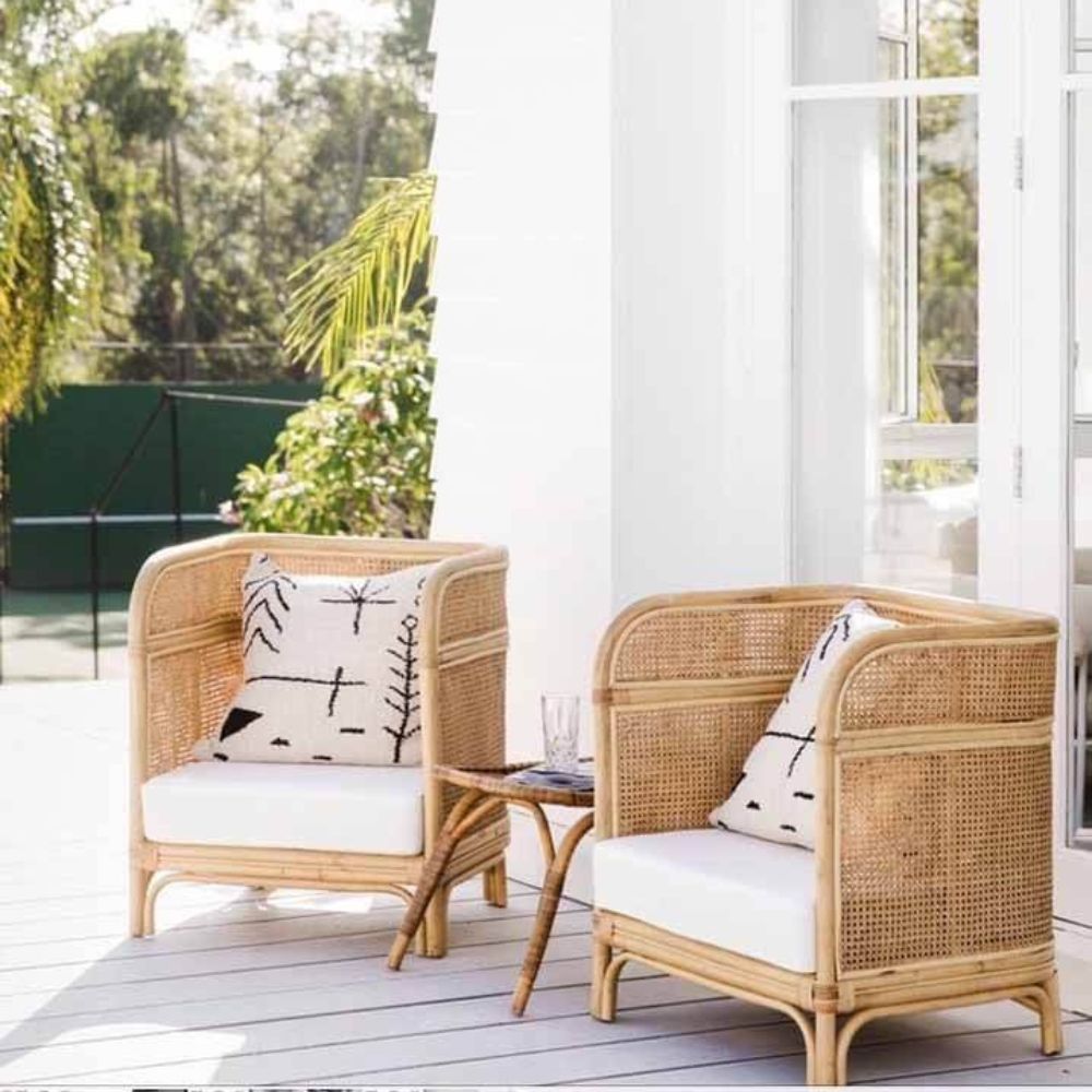 Espaço externo com cadeiras de vime e almofadas decorativas.