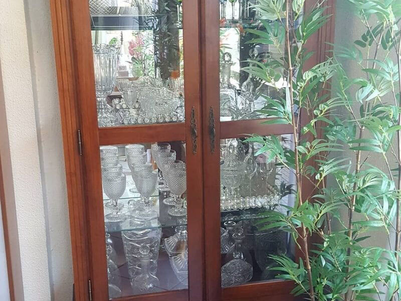 cristaleira de vidro e madeira com taças e copos de vidro