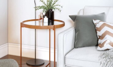 mesa lateral cobre ao lado de um sofá branco