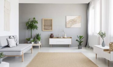 sala minimalista com parede cinza, móveis brancos e tapete marrom