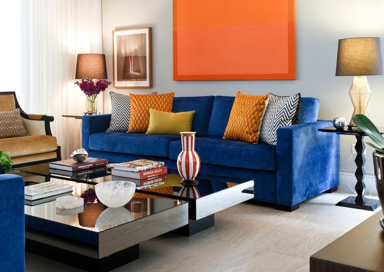 sala de estar decorada com sofá azul royal e quadro laranja