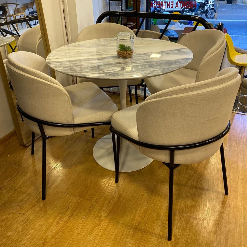mesa saarinen marmurizada ao lado de cadeiras confortáveis e estofadas