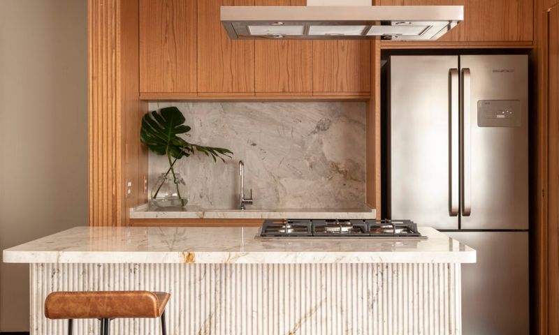 cozinha com balcão branco e parede de madeira