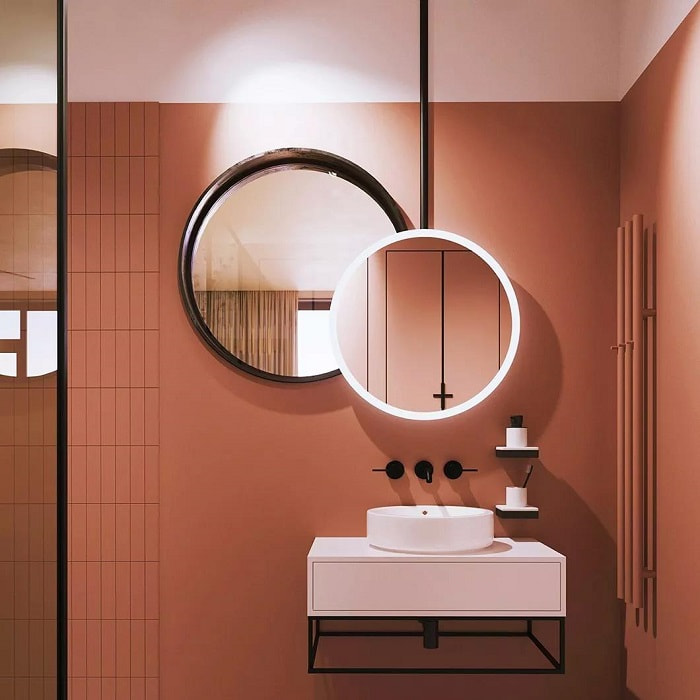banheiro moderno com espelho redondo e parede terracota