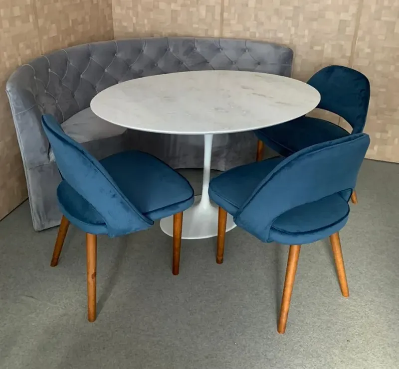 mesa saarinem com sofá em um canto e três cadeiras na cor azul em volta