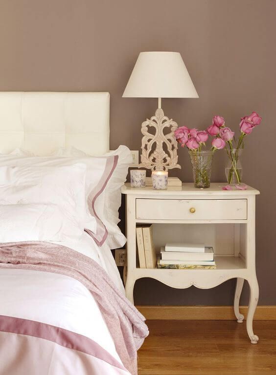 Cabeceira de cama com criado-mudo e flores