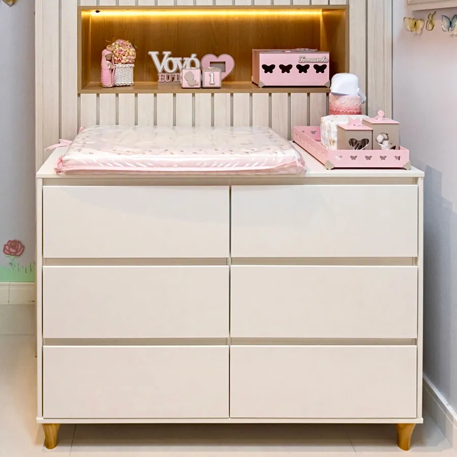 Trocar fraldas em cômoda rosa com decoração fofa.