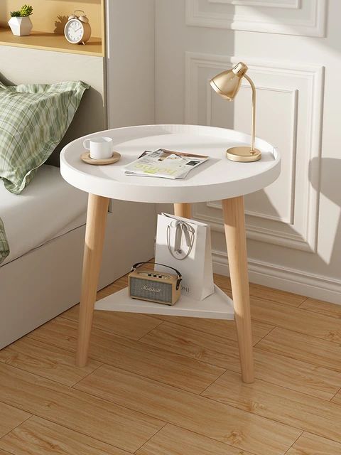 Mesa de cabeceira branca com abajur e itens decorativos.