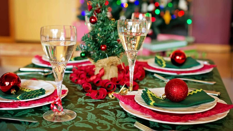 Mesa decorada para festa de Natal com taças e enfeites.