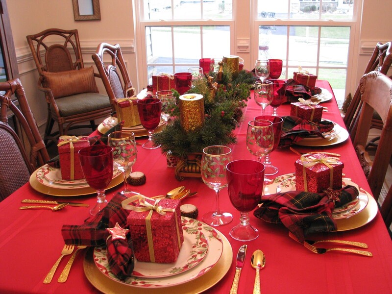 Mesa de Natal decorada com pratos e presentes vermelhos.