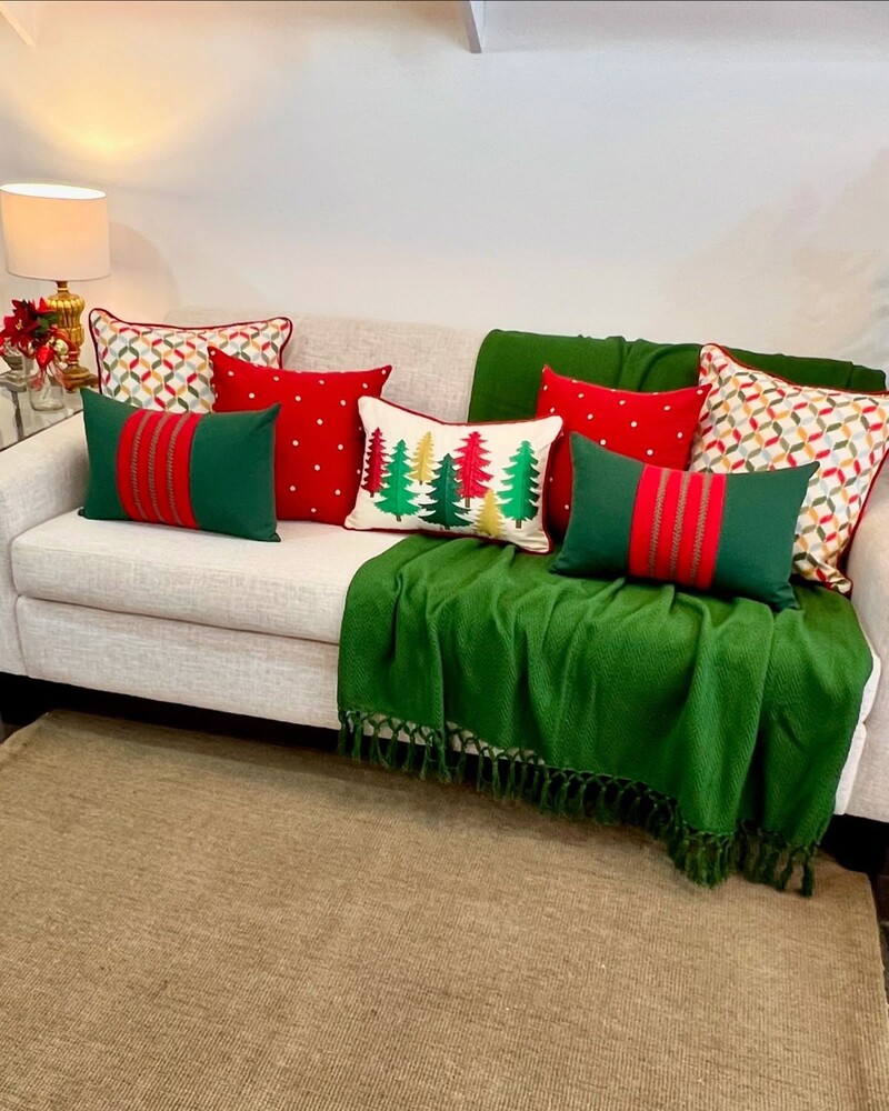 Sofá decorado com almofadas e manta natalina.