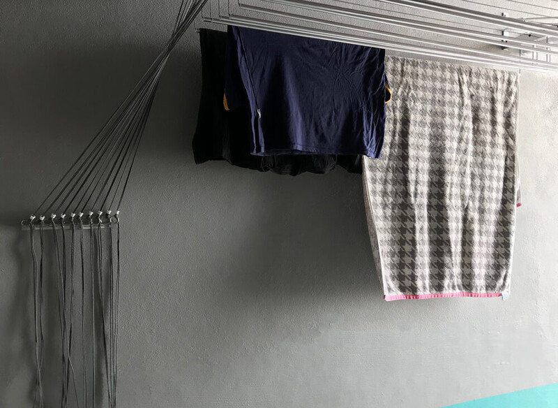 Roupas secando em varal na parede cinza