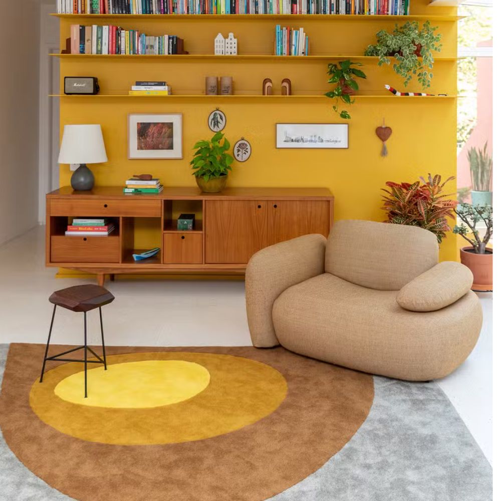Sala moderna com sofá curvo e prateleira amarela.