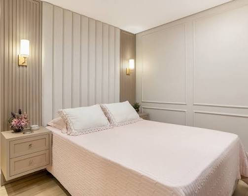 Quarto decorado com cama e paredes em tons neutros